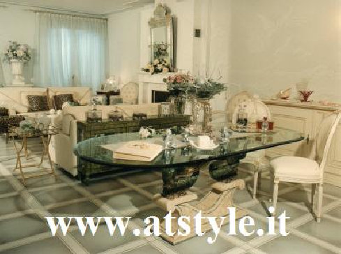 Credenza in legno massello laccata in bianco e oro antico, sedie in stile Luigi XVI in tessuto capiton�e, tavolo ovale con piano in 
cristallo.